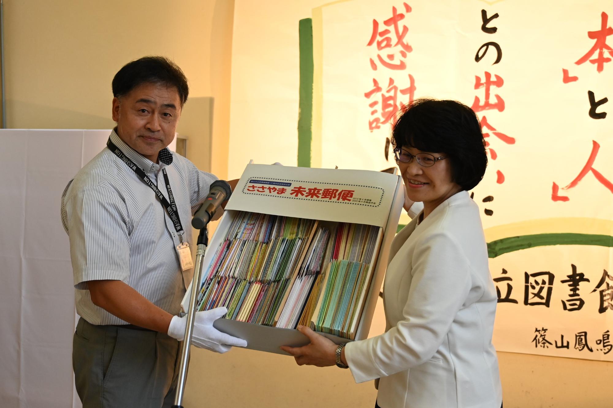 図書館長から丹南郵便局長へささやま未来郵便の引き渡し