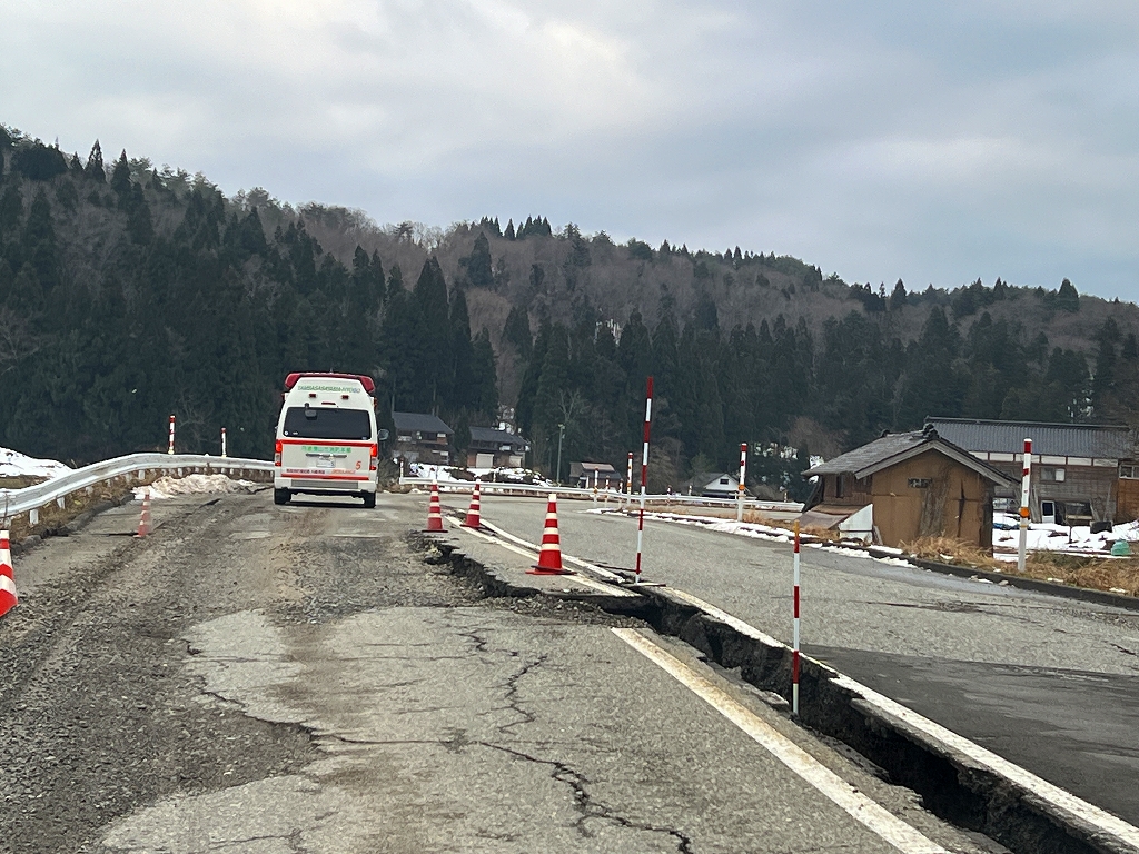 能登町にて割れているところがある地面を走る丹波篠山市の救急車。