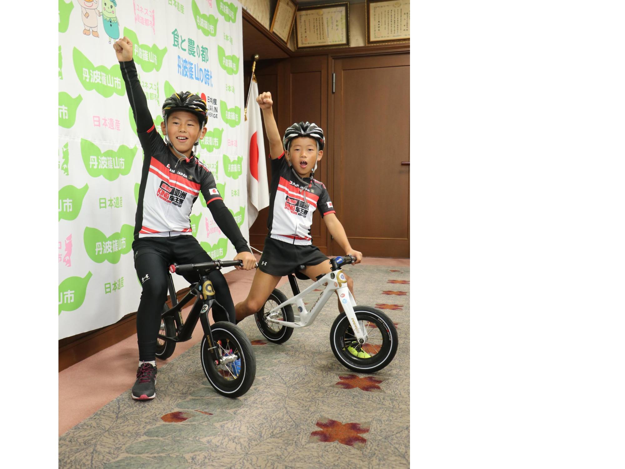 バイクに乗って片腕を上げたポーズをとる片桐兄弟