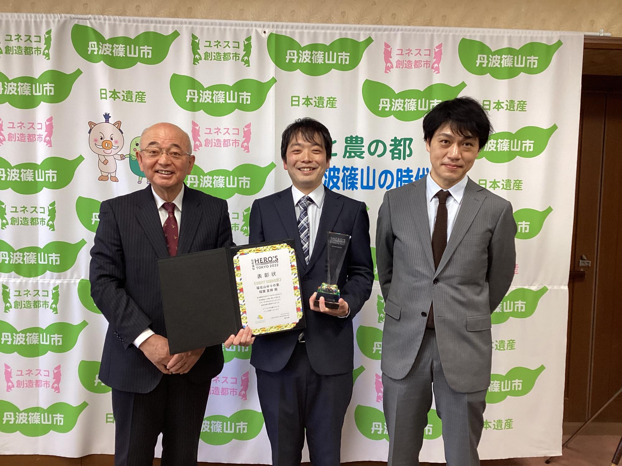 市長、施設長、表彰状とトロフィーを持った稲葉さんの記念撮影