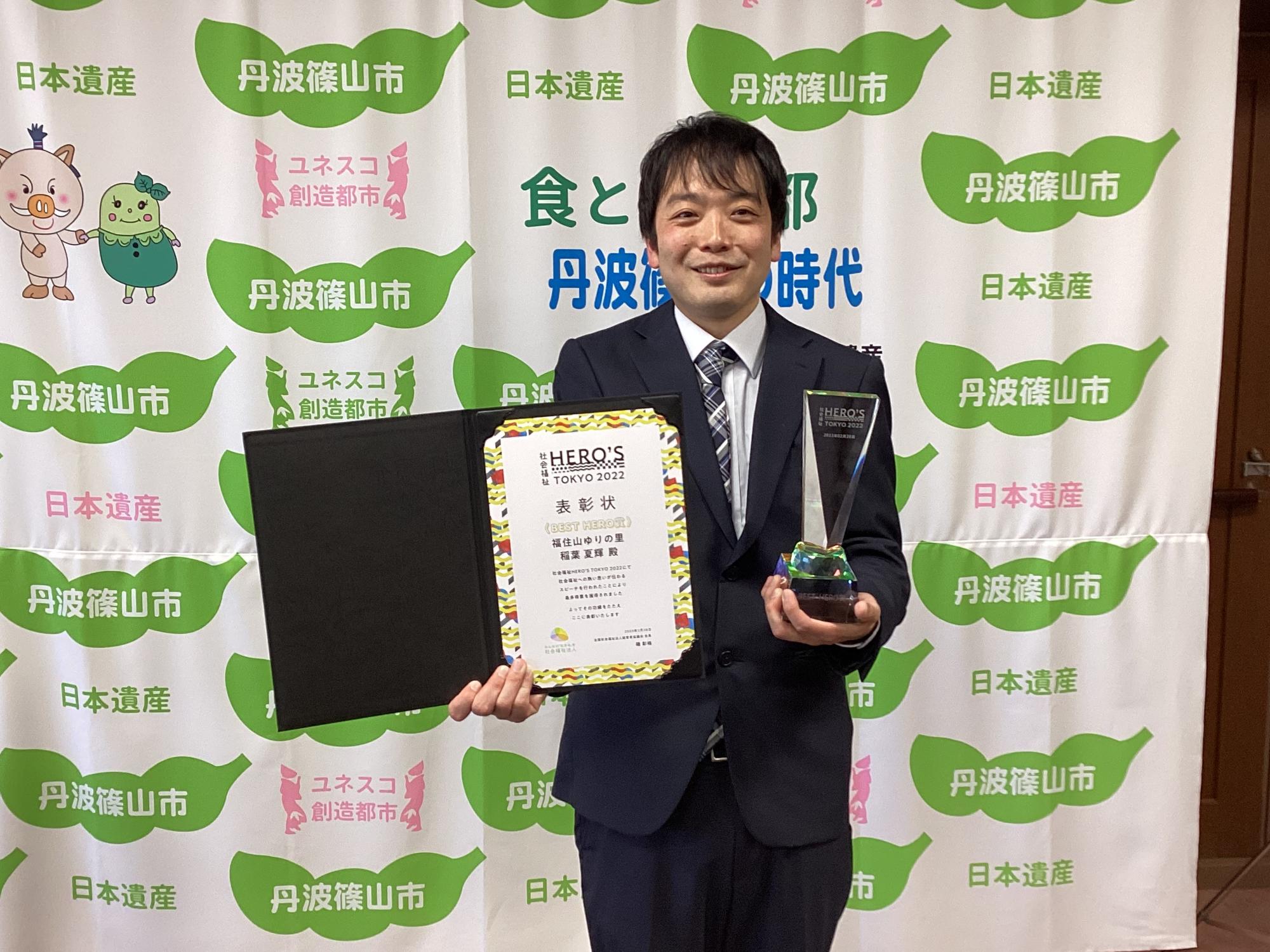 ベストヒーローズ賞を受賞した稲葉さんが、表彰状とトロフィーを持って記念撮影