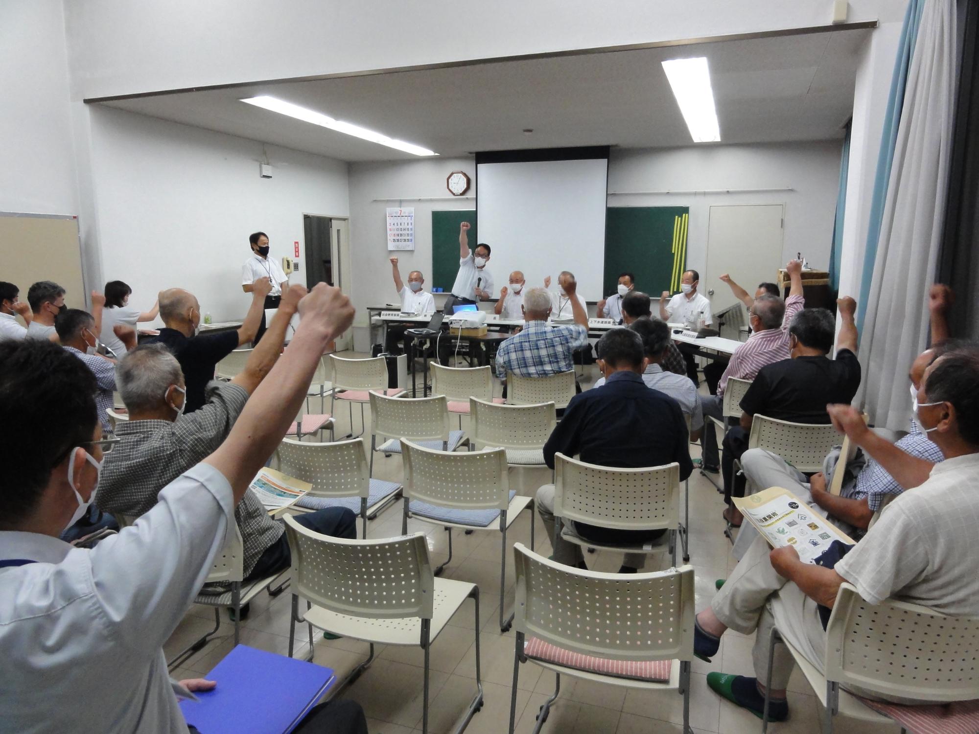 会議の最後に、参加者全員でこぶしを出して「ガンバロー」と言っている