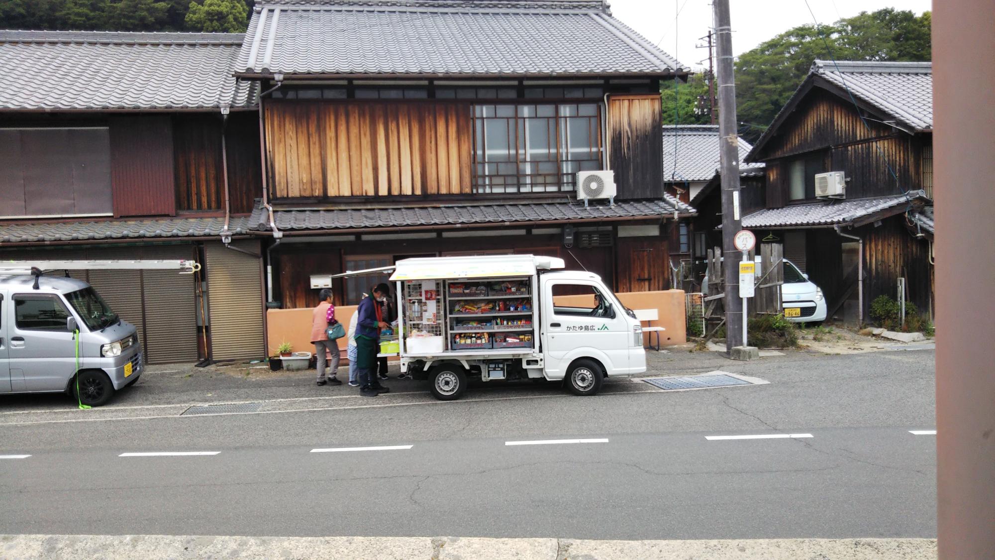 住宅の前で移動販売車が駐車して何人か買い物している
