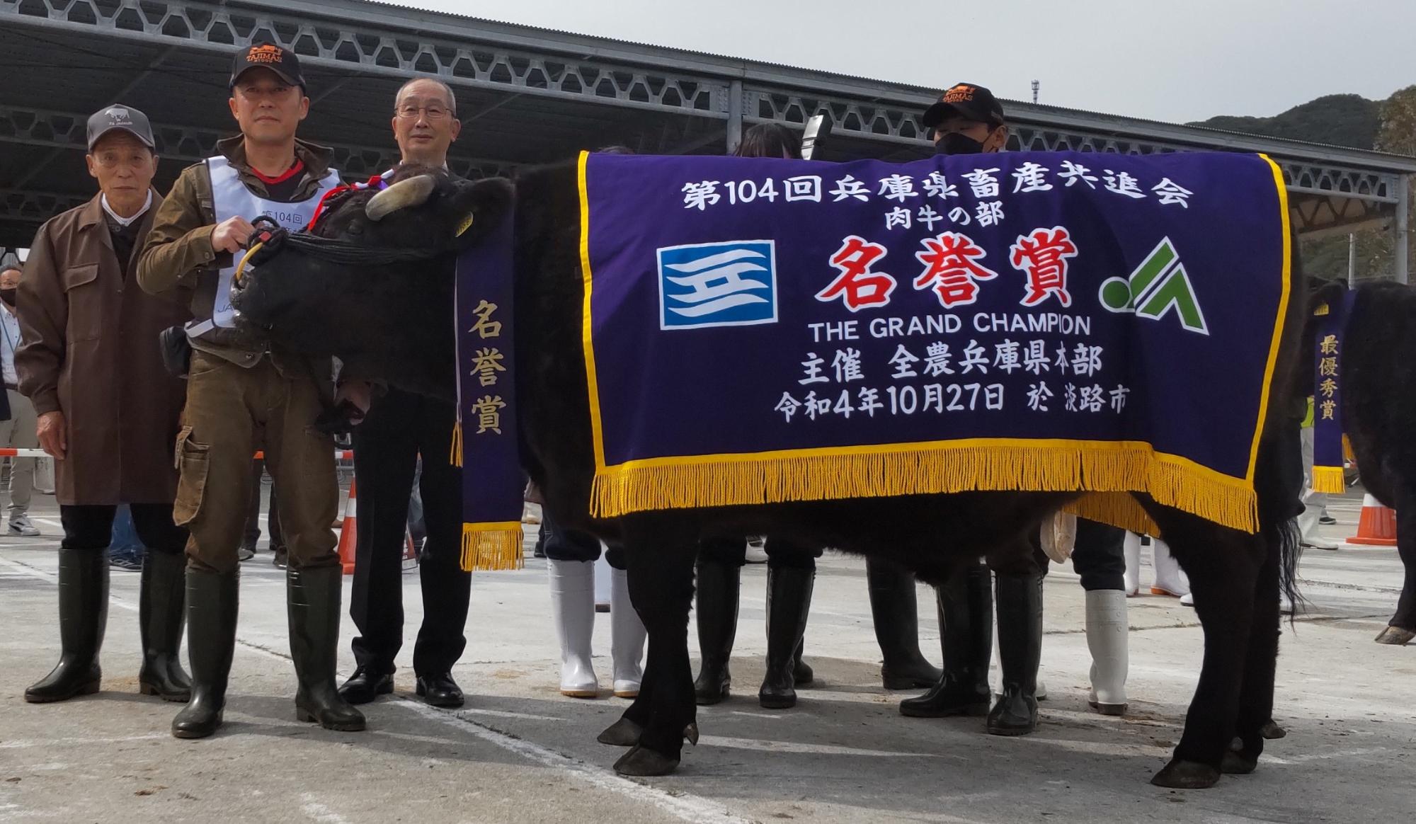 名誉賞という横断幕を牛にかけて田中さんと関係者の方が記念撮影
