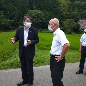 スーツを着た男性と市長が、ほ場の前で話をしている