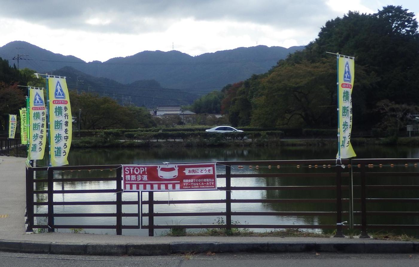 お堀の柵に横断歩道で止まりますの横断幕が掲示してある