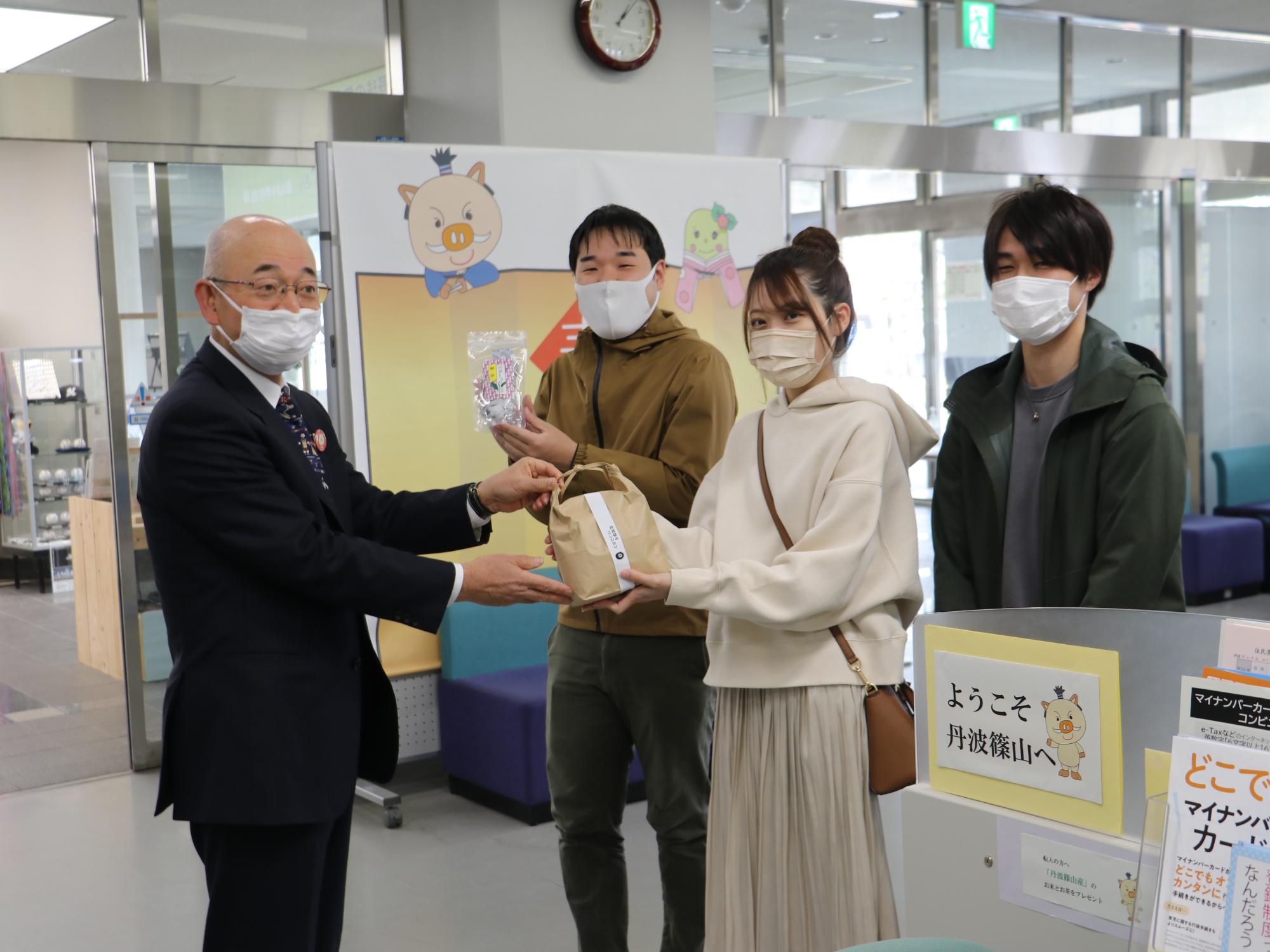 市長が転入者の方におもてなし事業のお米やお茶を手渡ししている