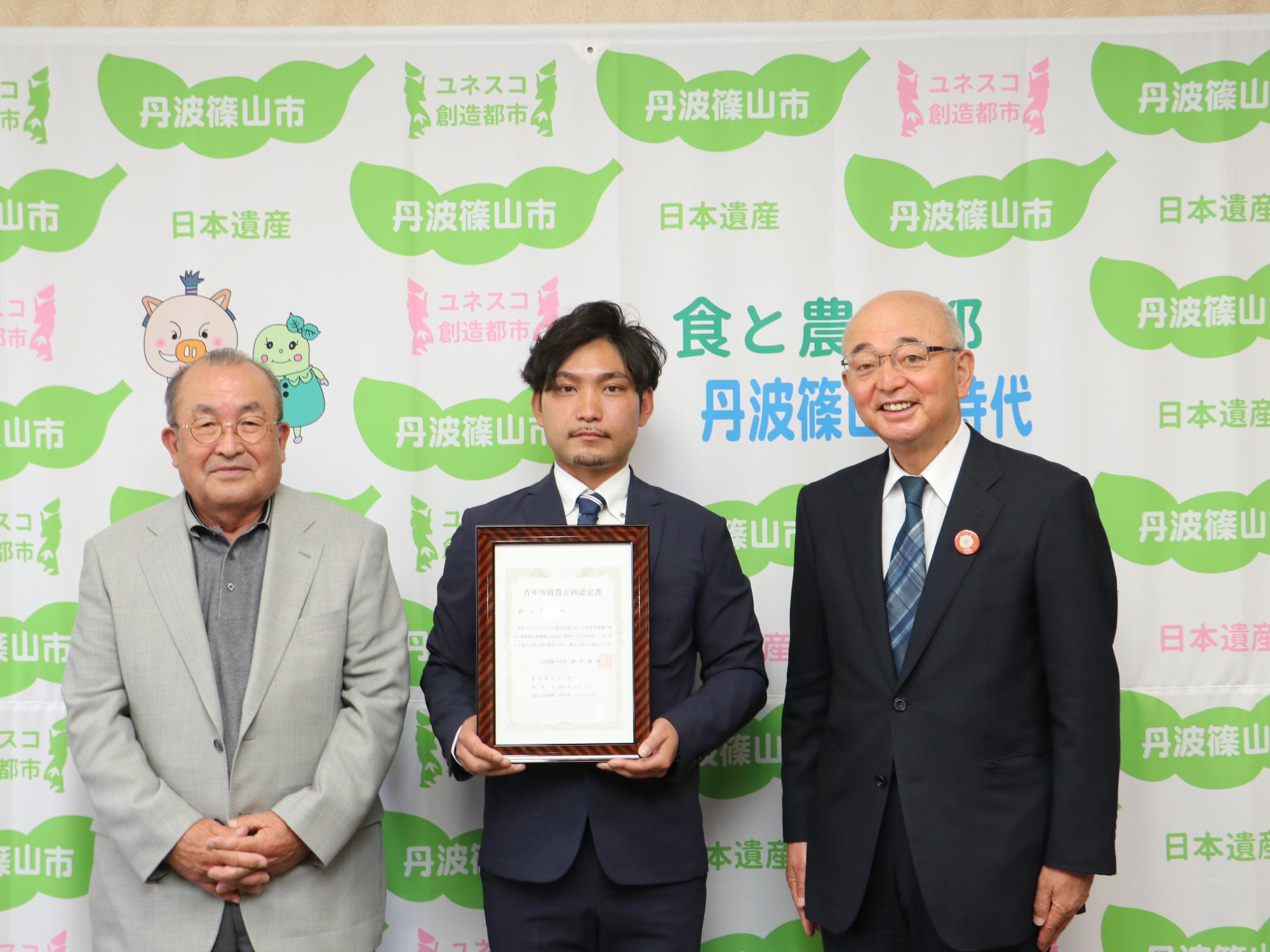 認定証を持った村上さん、両隣に市長と地元営農組合の酒井さん