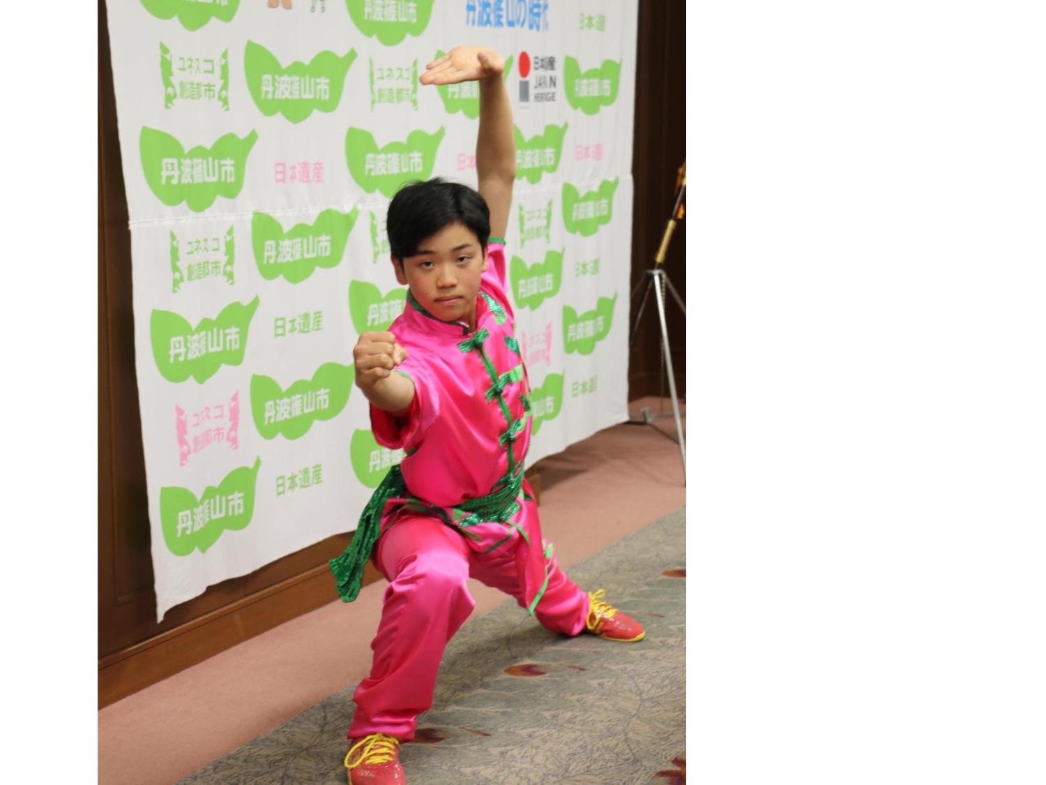 ピンク色の衣装を着た男の子が太極拳の演舞を披露している