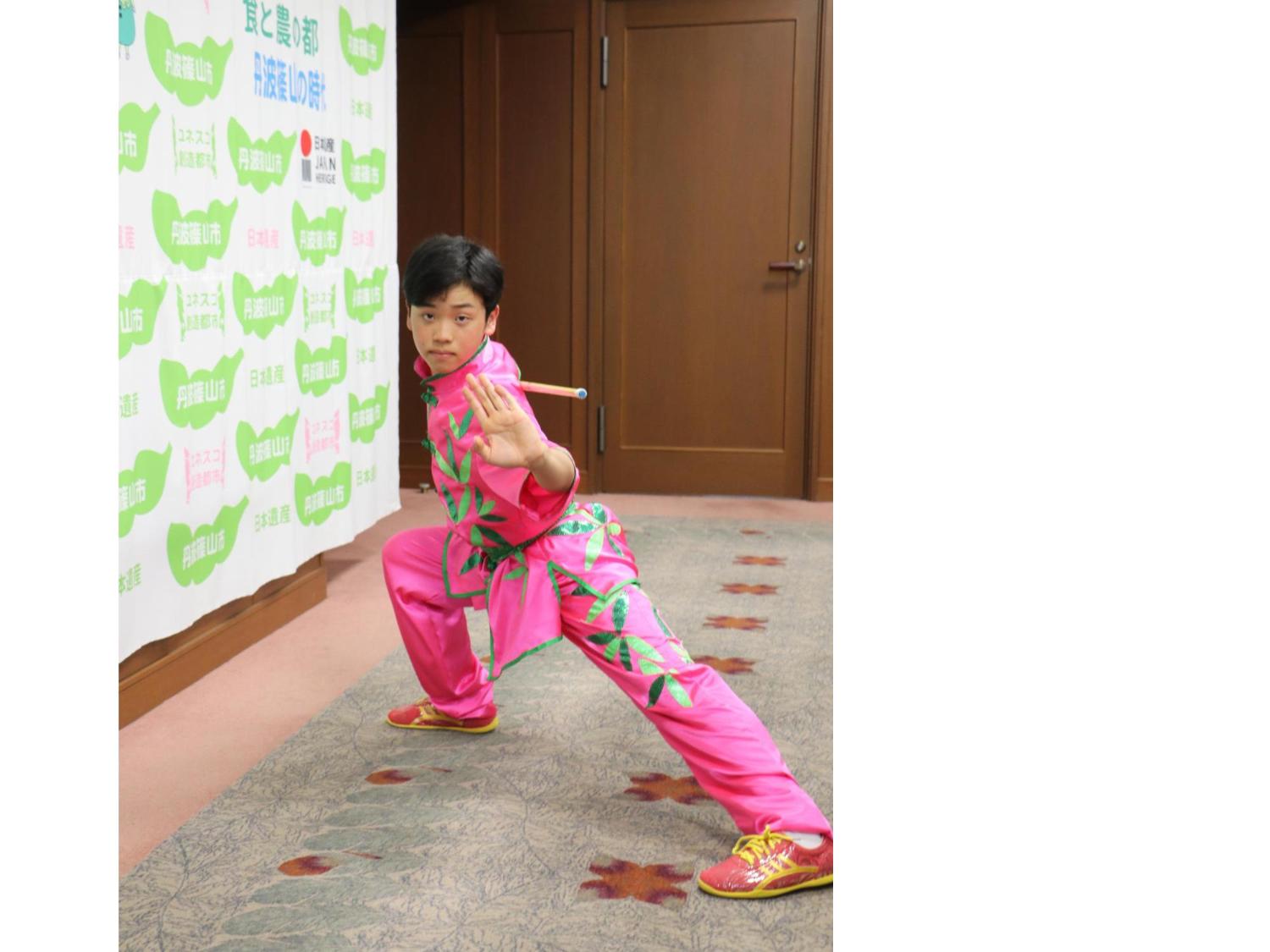 ピンク色の衣装を着た男tの子が太極拳の演舞を披露している