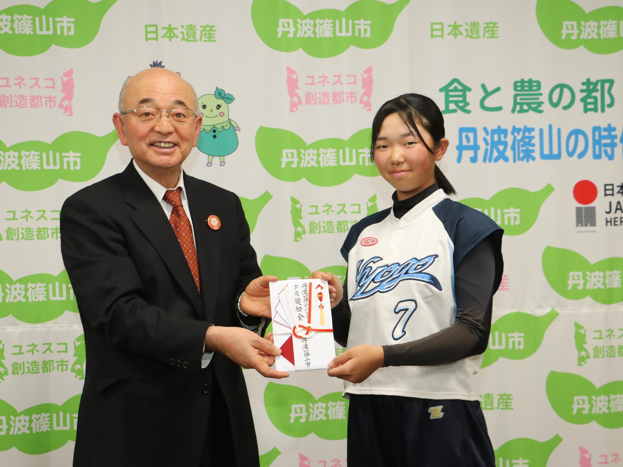 市長が、県選抜に選ばれた女の子に奨励金を渡している