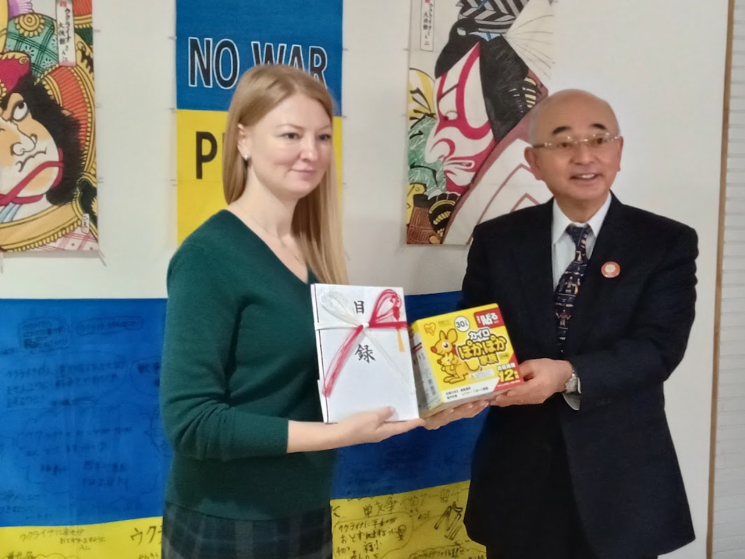 市長が大使館の方へ目録とカイロを渡されている