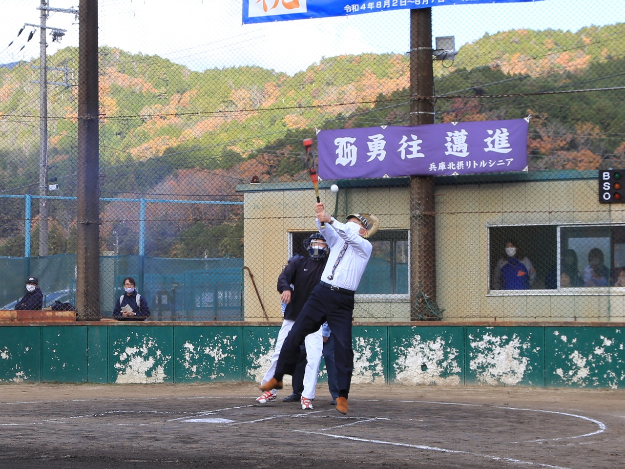 野球大会の始球式で、市長が高めのボールを何とか打とうとしている