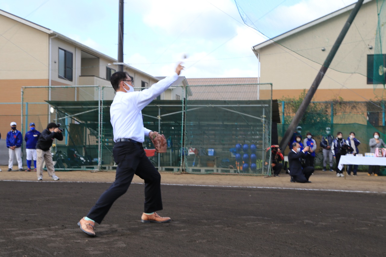 教育長が野球大会の始球式でボールを投げている