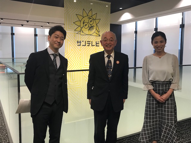 サンテレビのロゴの前で木内アナウンサー、小林さん、市長の記念撮影