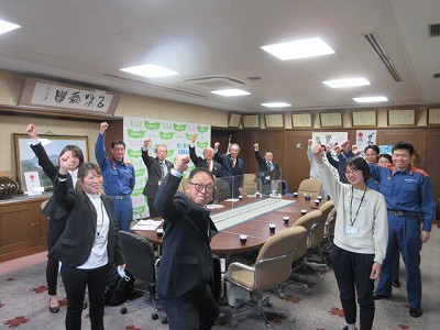 市長や教育長、幹部職員と若手職員がおーと手をあげて記念撮影