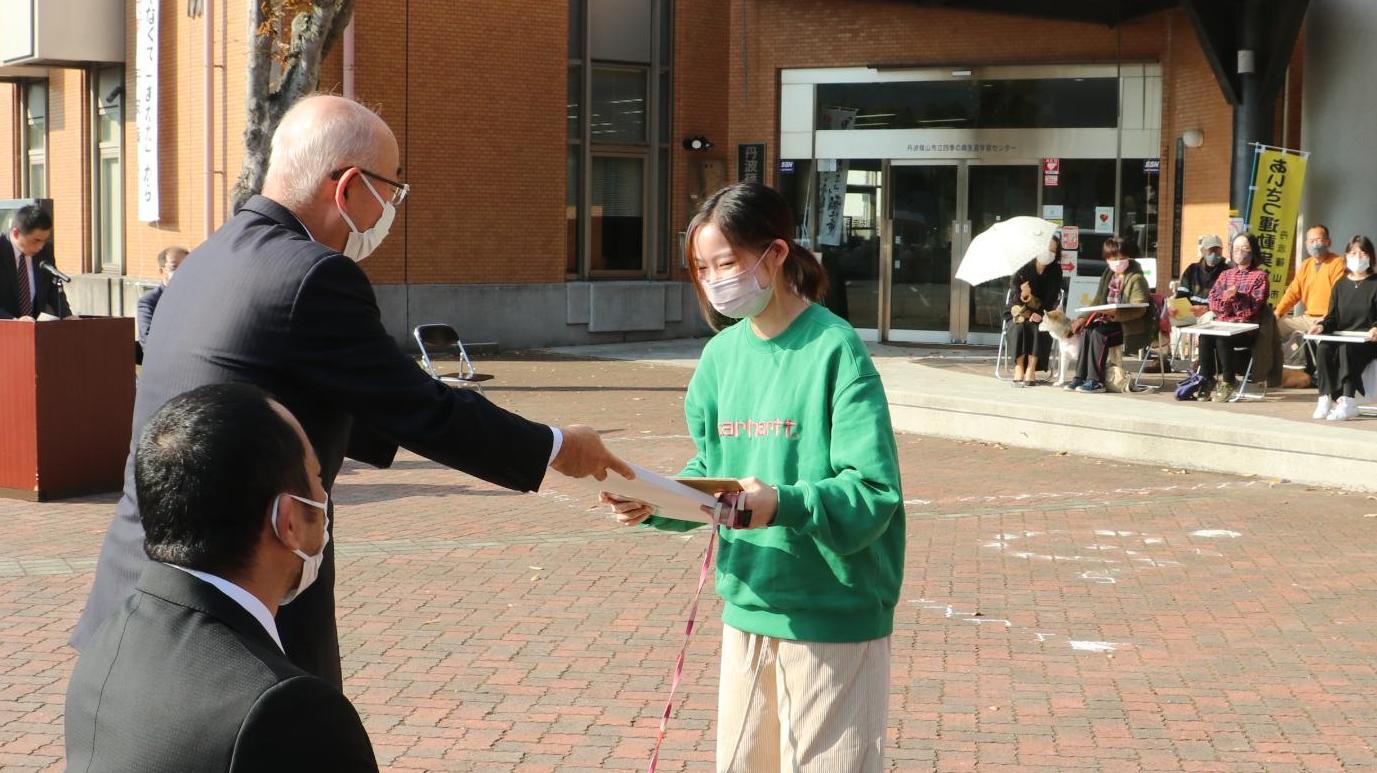 飼い主に表彰状を手渡している