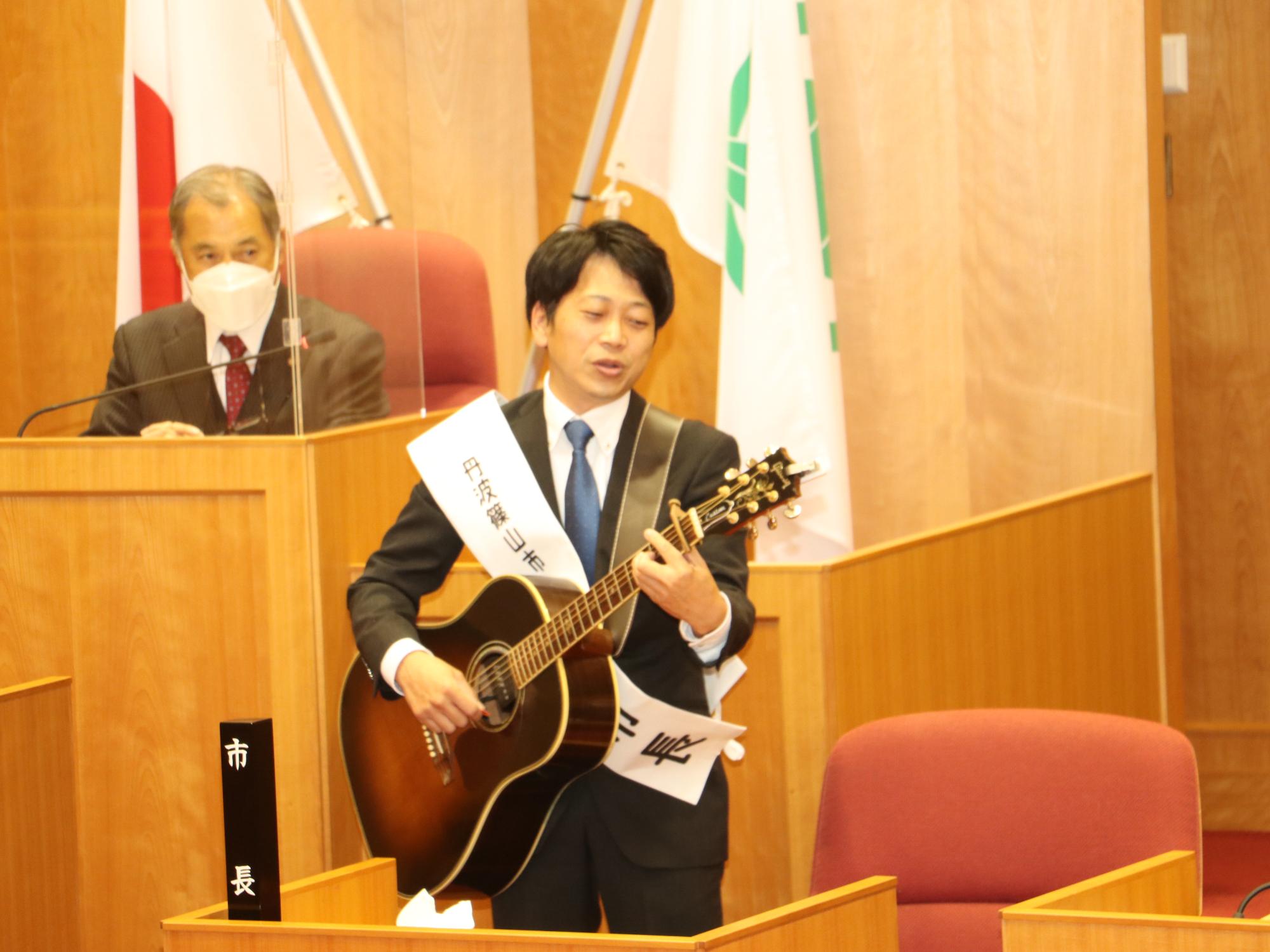 1日市長の雄介さんが、議場で弾き語っている