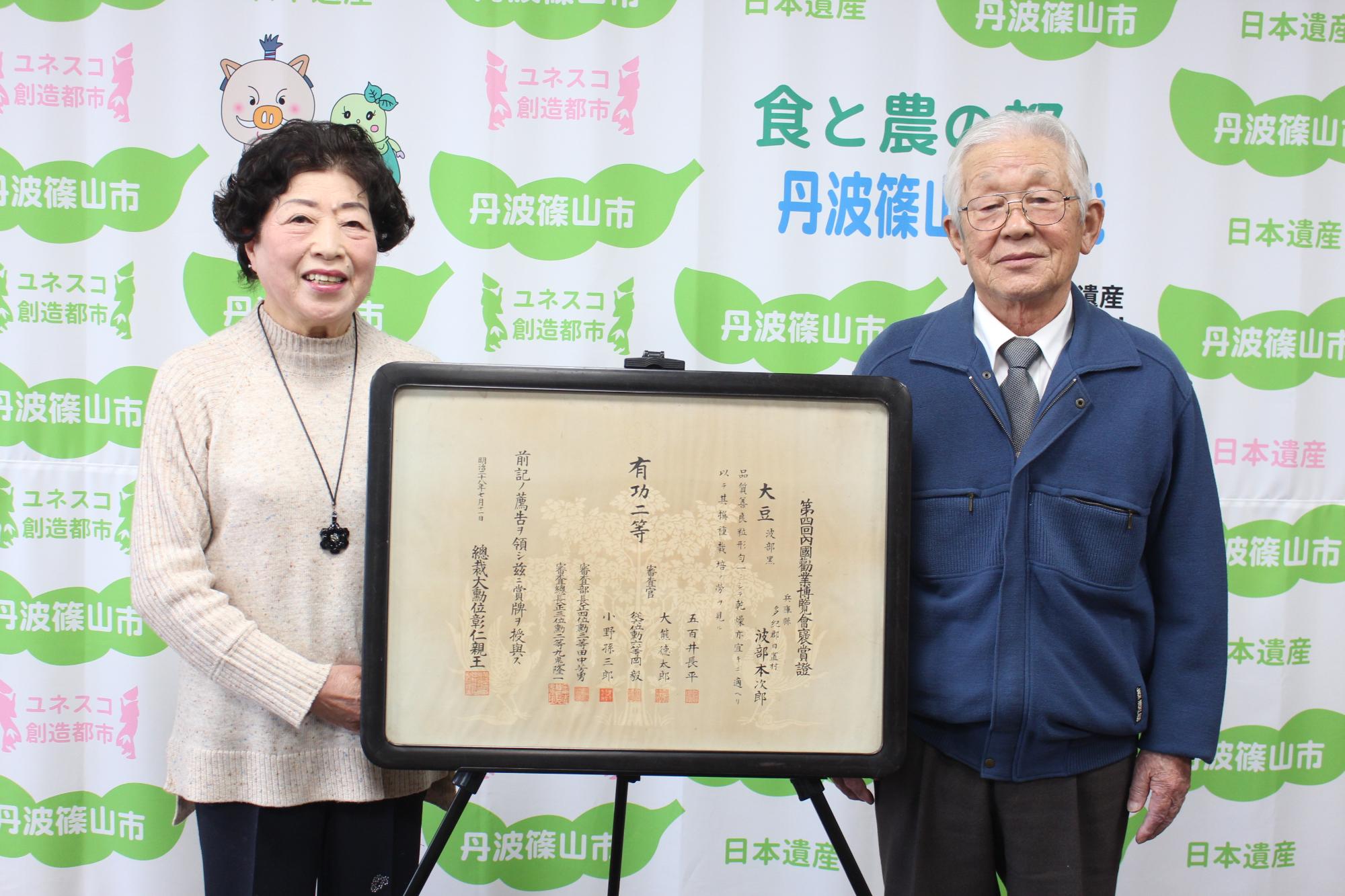 寄贈していただく褒賞証とご夫婦での記念撮影