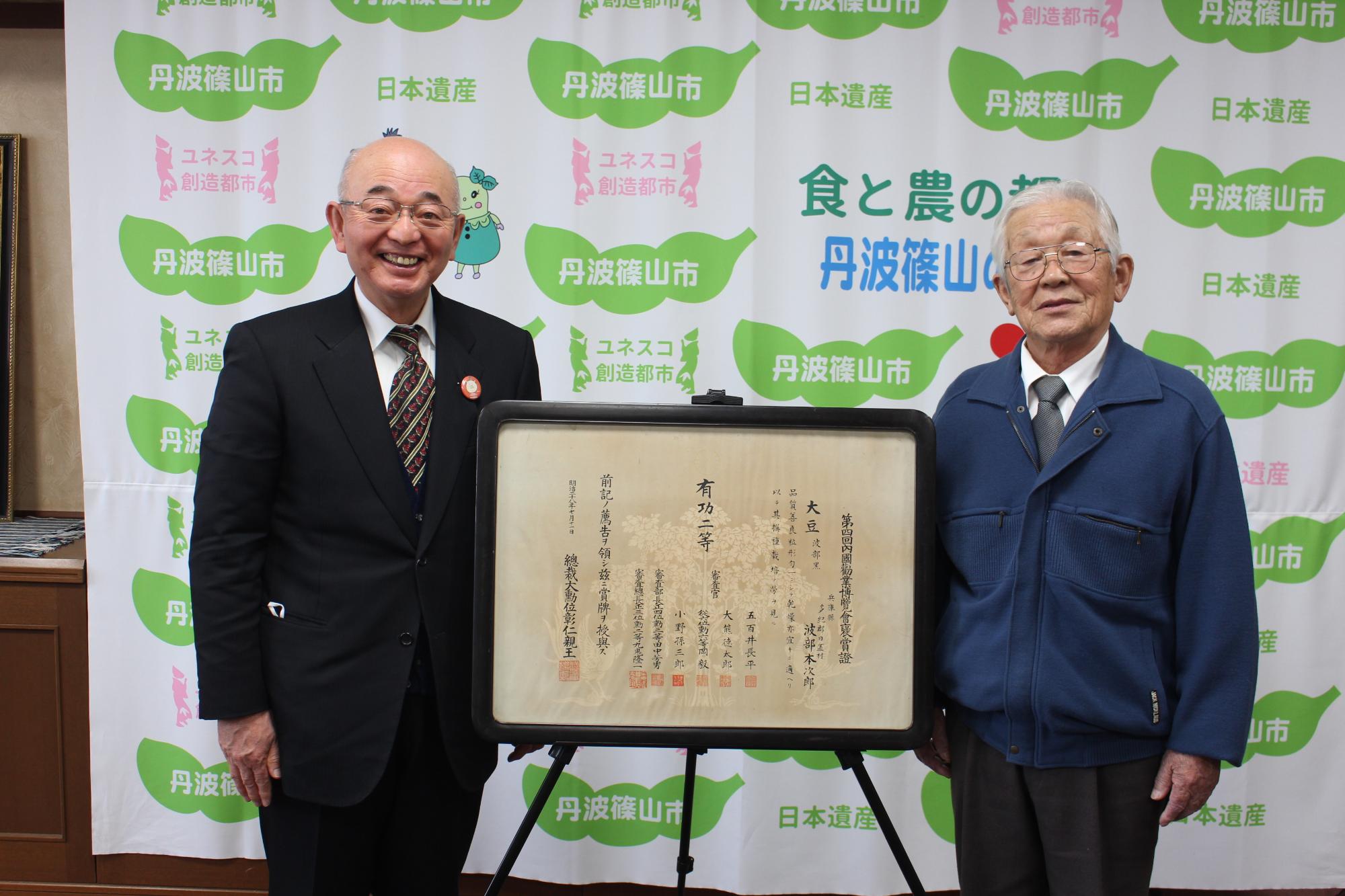 寄贈していただく褒賞証と、市長、寄贈者の記念撮影