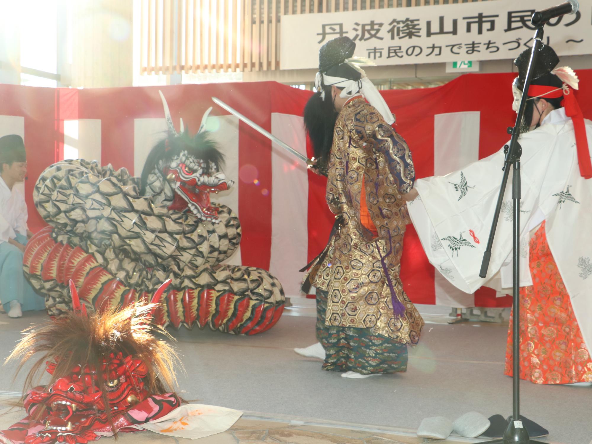 神楽で、剣を持ち竜と対峙している