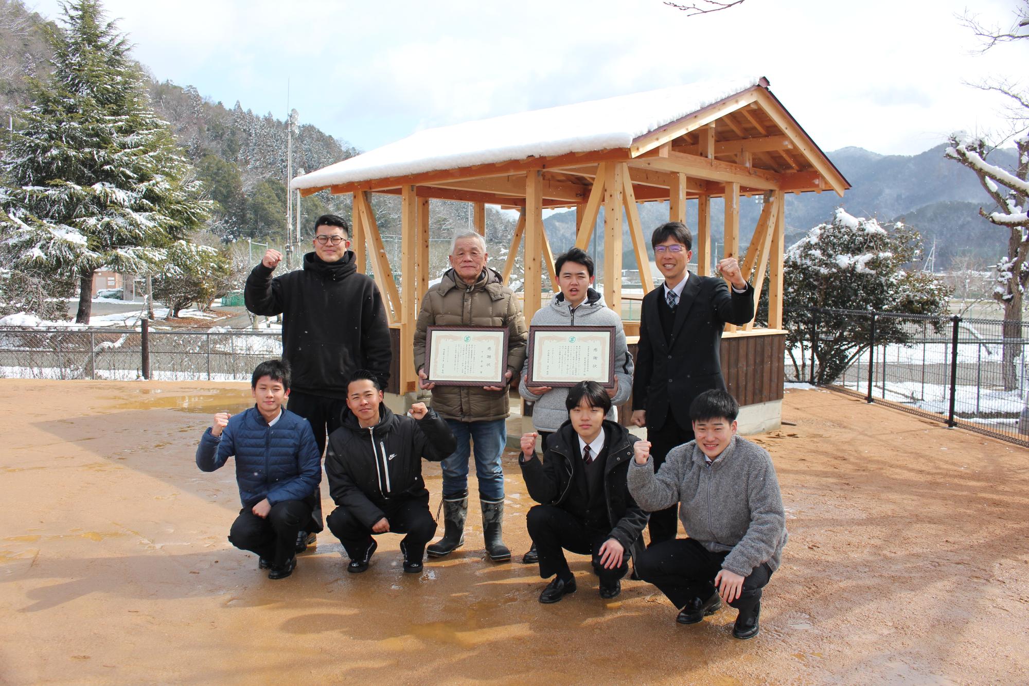 完成した東屋の前で、中井工務店、篠山産業高校の生徒たちが記念撮影している
