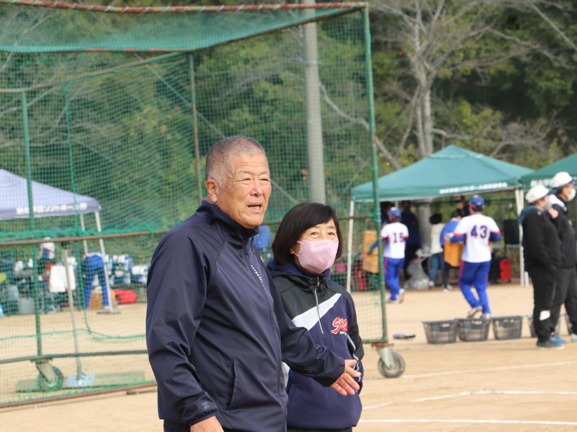 ソフトボールの交流試合で長澤先生が様子を見守っている