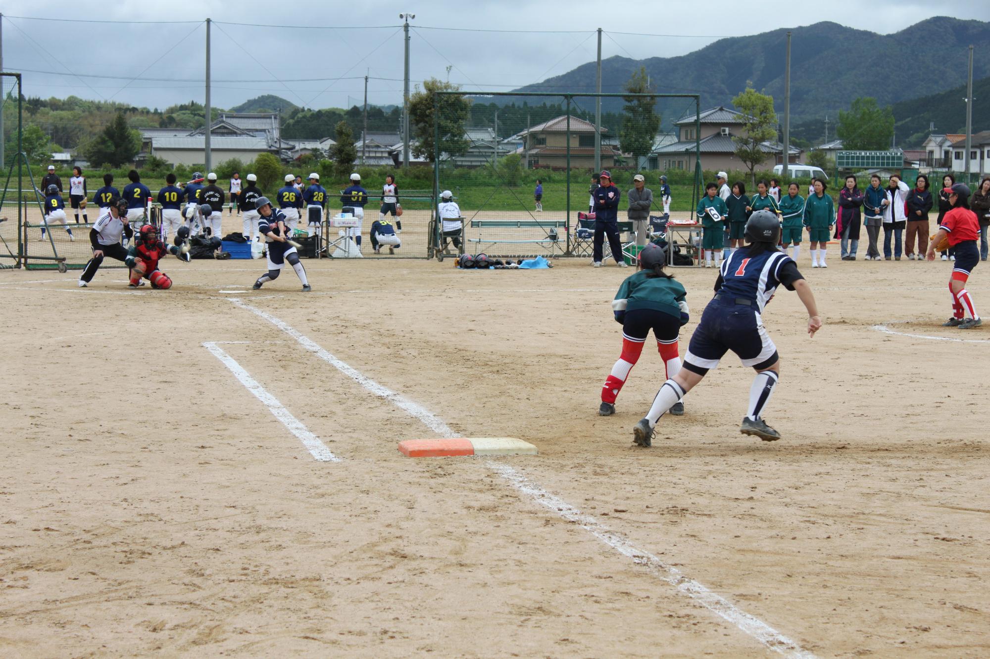 ソフトボールの試合で、バッターが打ち、ファストランナーがスタートしようとしている