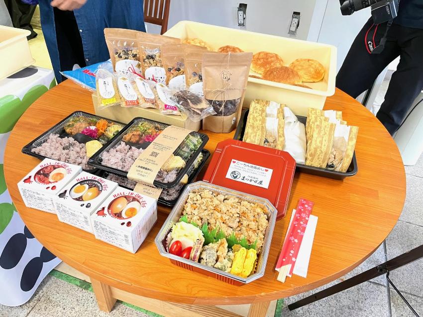 テーブルの上に、丹波篠山スクエアで販売予定のパン、弁当、ちまき、お菓子が並んでいる