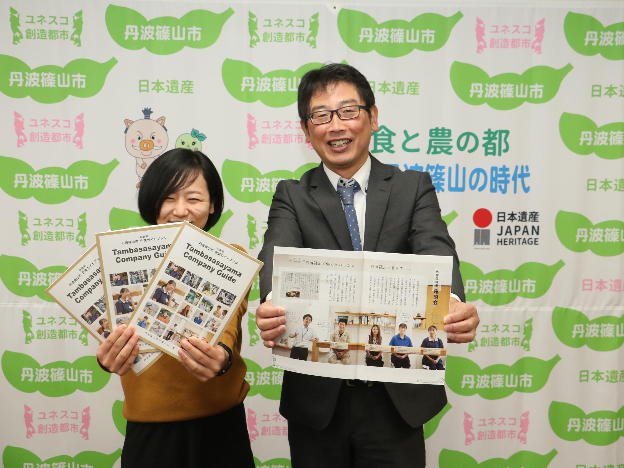 職員2名が完成した企業ガイドブックを持って記念撮影