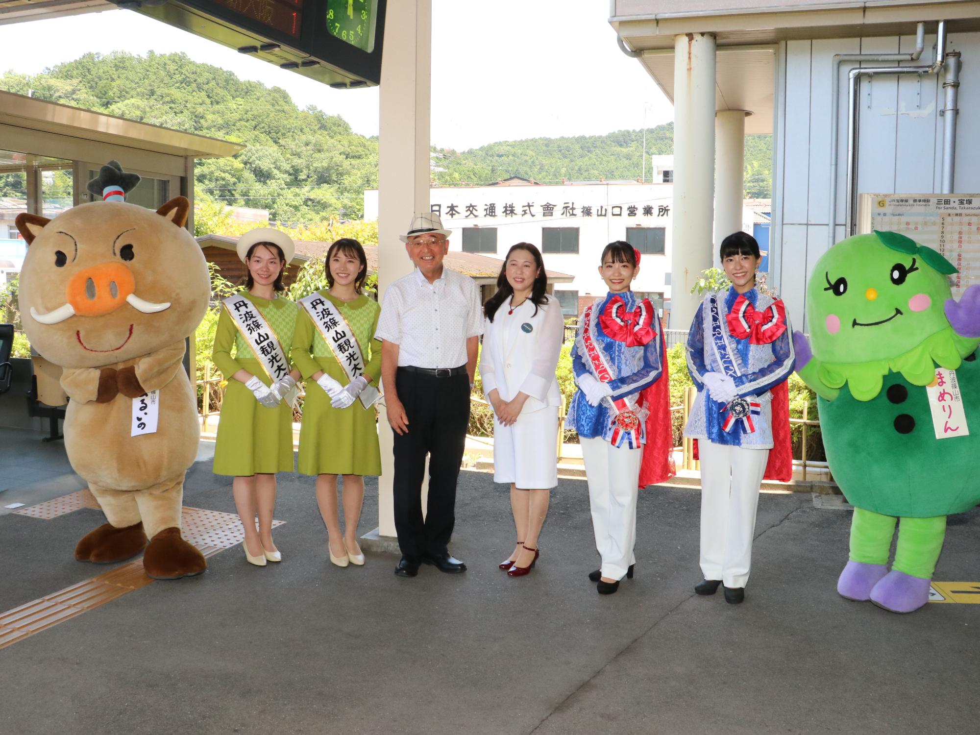 酒井市長、宝塚市山崎市長、その両隣に観光大使とまるいのまめりんが並んでいる