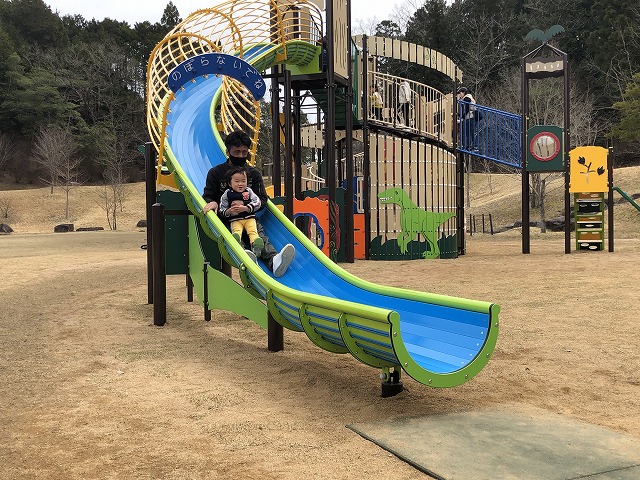 お父さんに抱っこしてもらって小さいこどもがすべりだいを滑っている