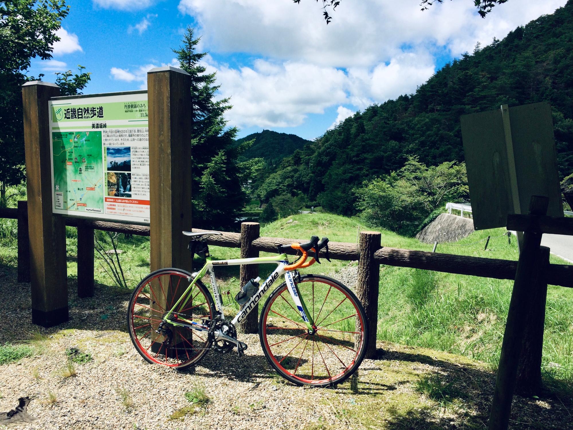 峠に遊歩道の看板があり、柵に自転車が立てかけてある