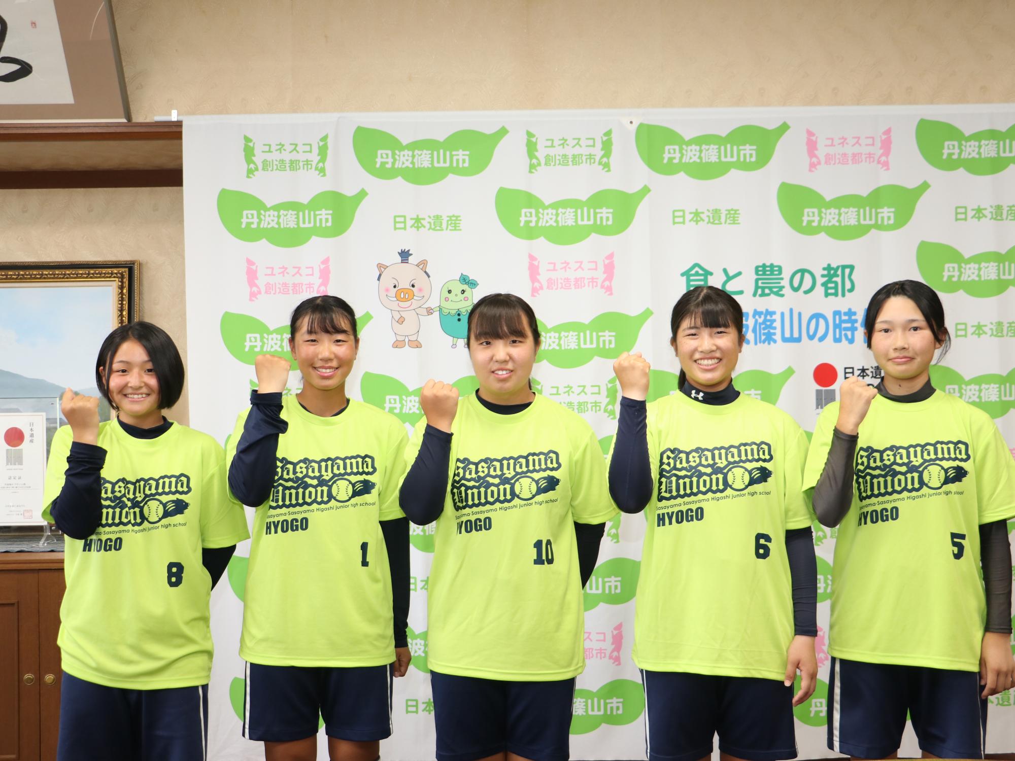 おそろいのTシャツを着た女の子5人がガッツポーズしている