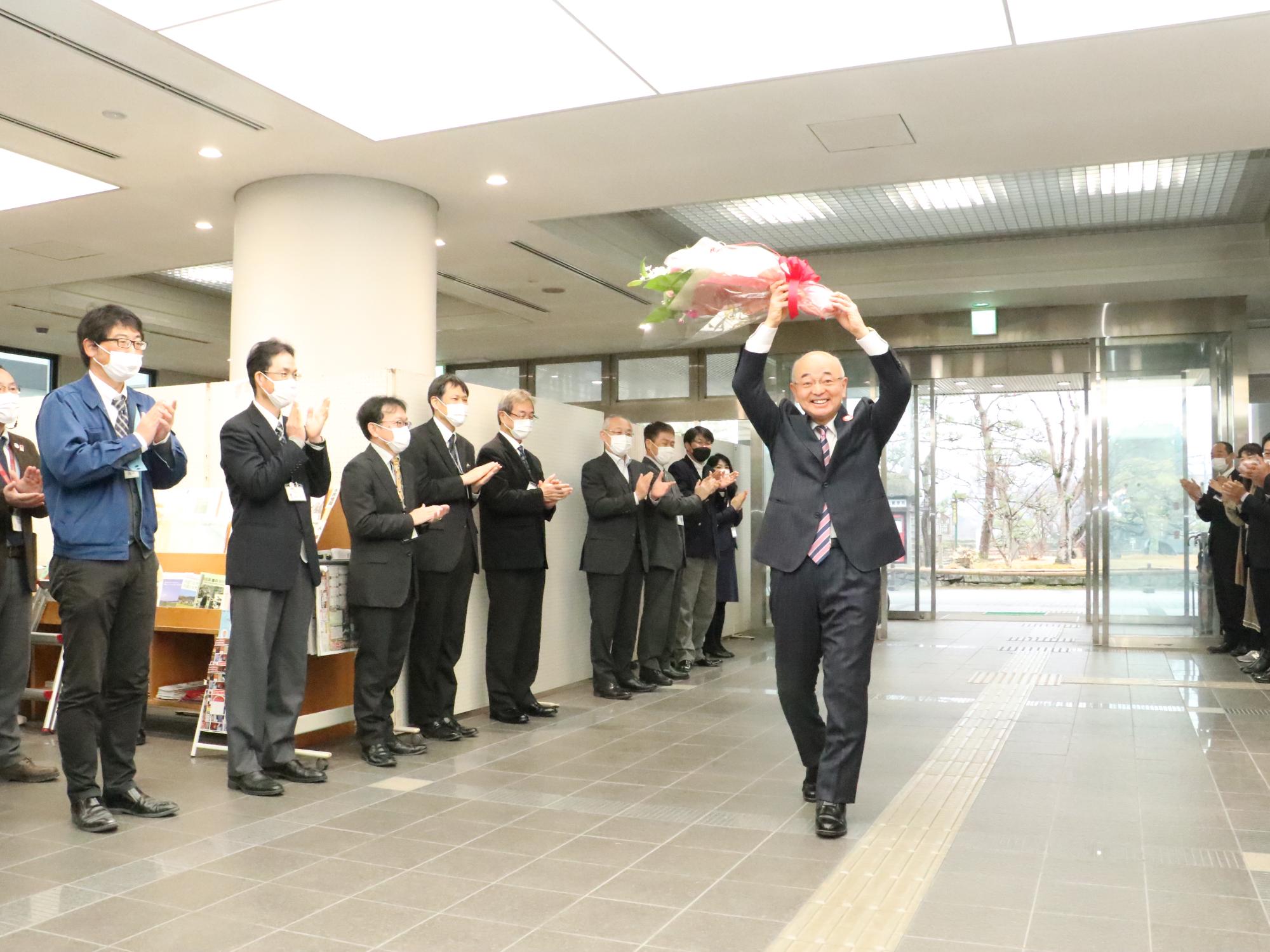 花道の中央を、市長が花束を頭上に掲げて歩いている
