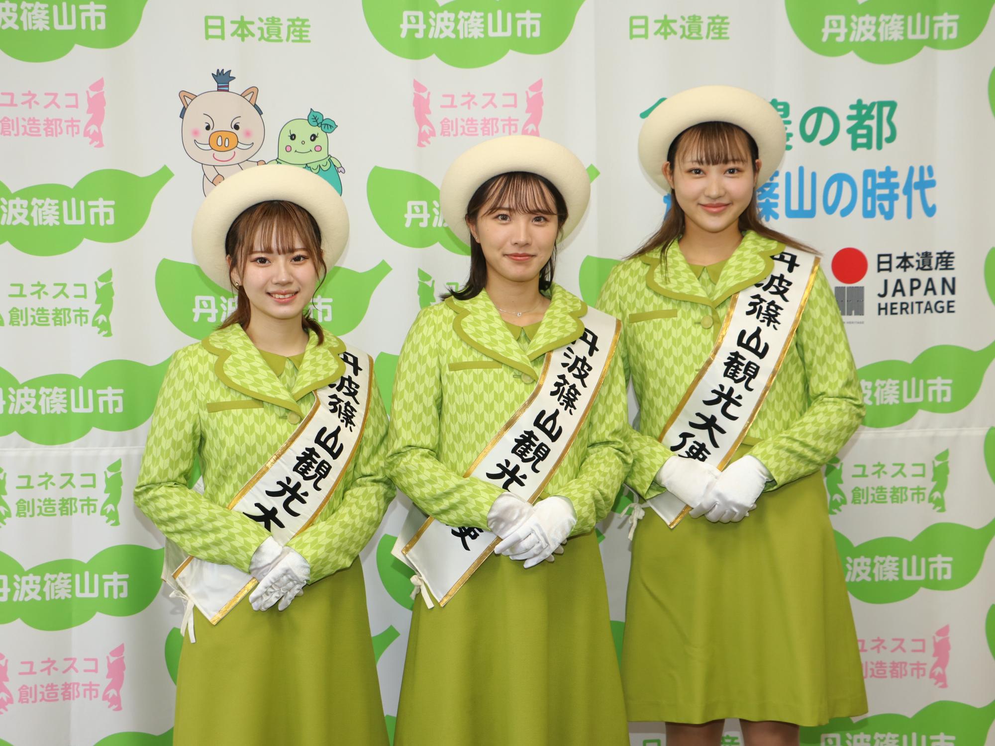 任命式で、観光大使の制服を着た3人の女性の記念撮影