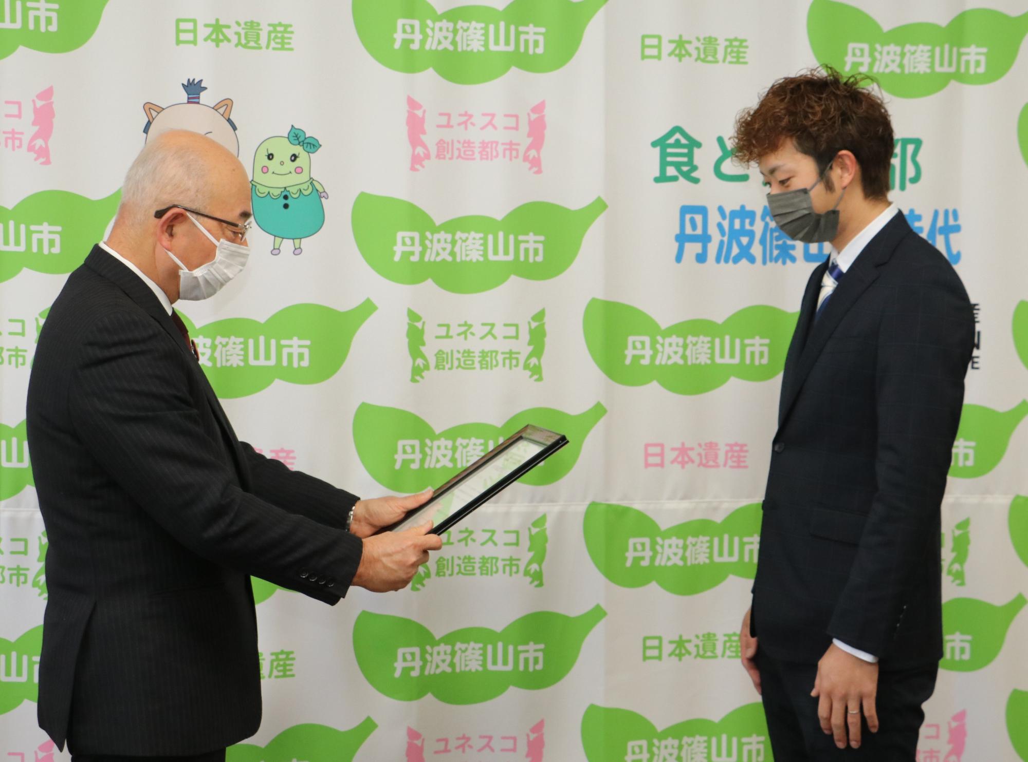 市長が認定書を手渡そうとしている