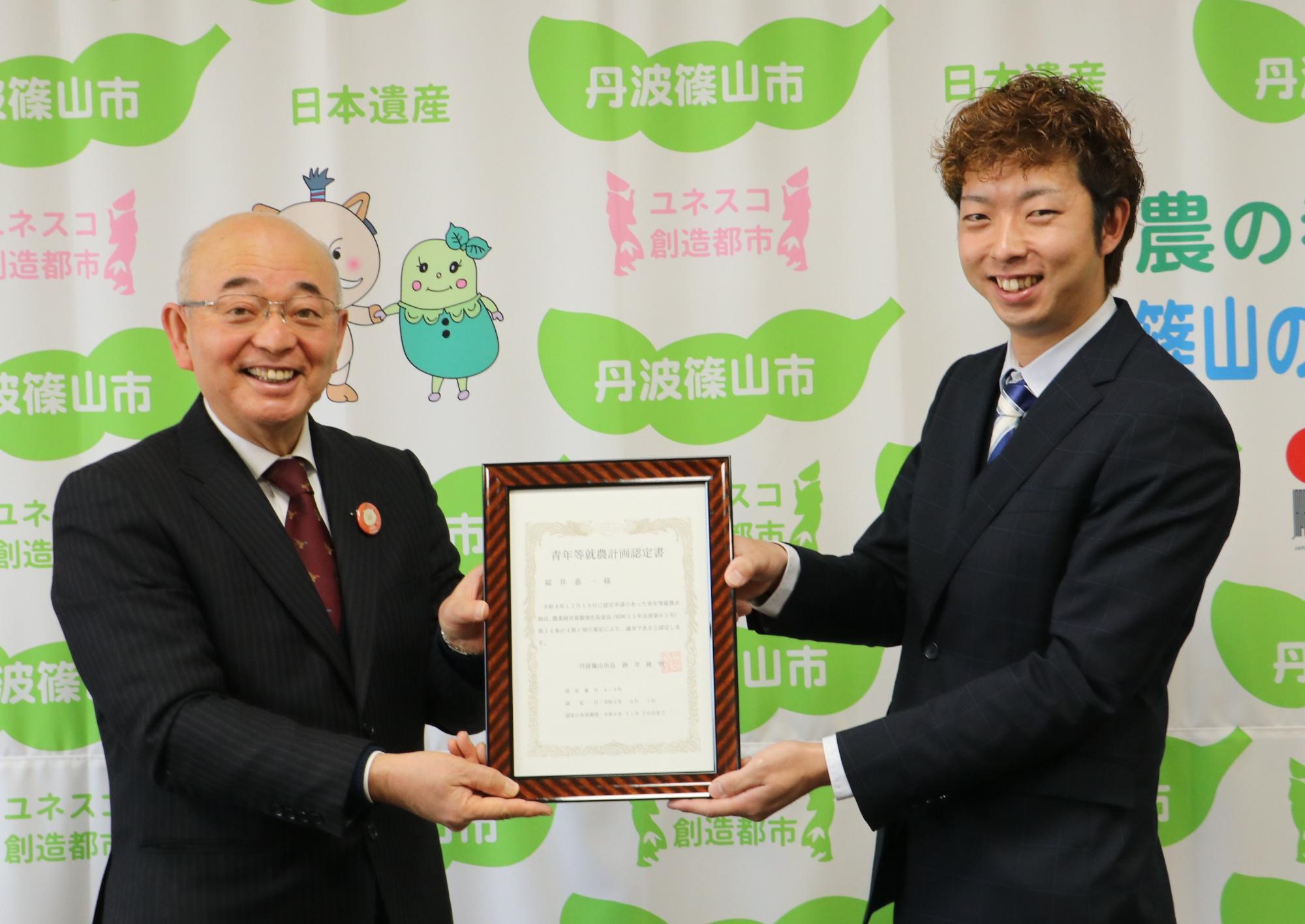 市長と認定新規就農者が、認定書を一緒に持っている
