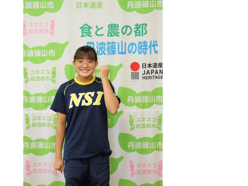 水泳クラブのユニフォームを着た女の子がガッツポーズをしている