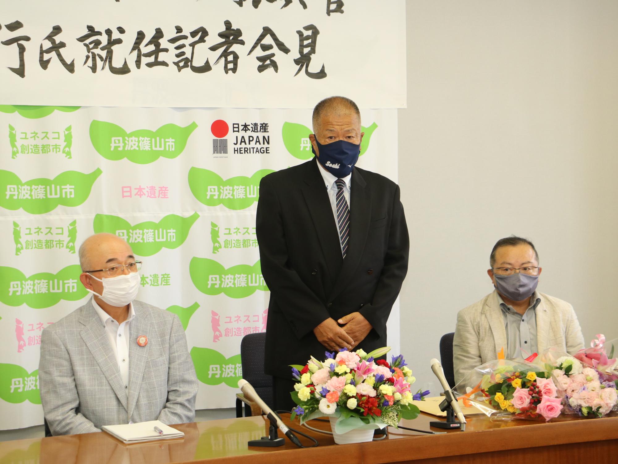 記者会見で長沢先生が立ってあいさつされている