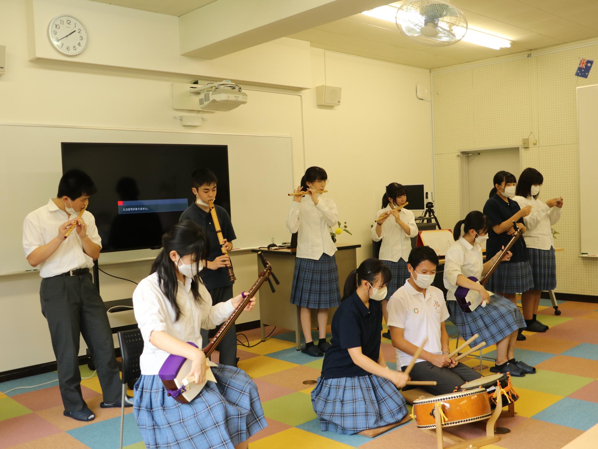高校生のこどもたちが、知事と一緒に太鼓や三味線、尺八などを演奏している