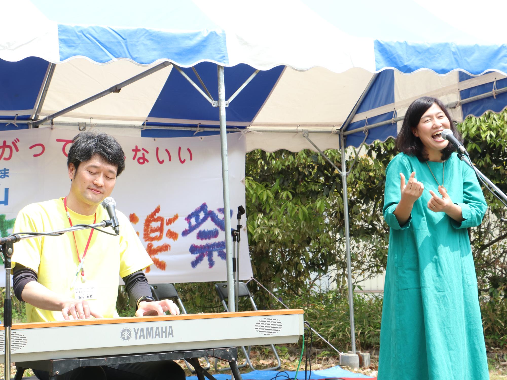 男性がキーボードを弾き、女性が立って歌っている