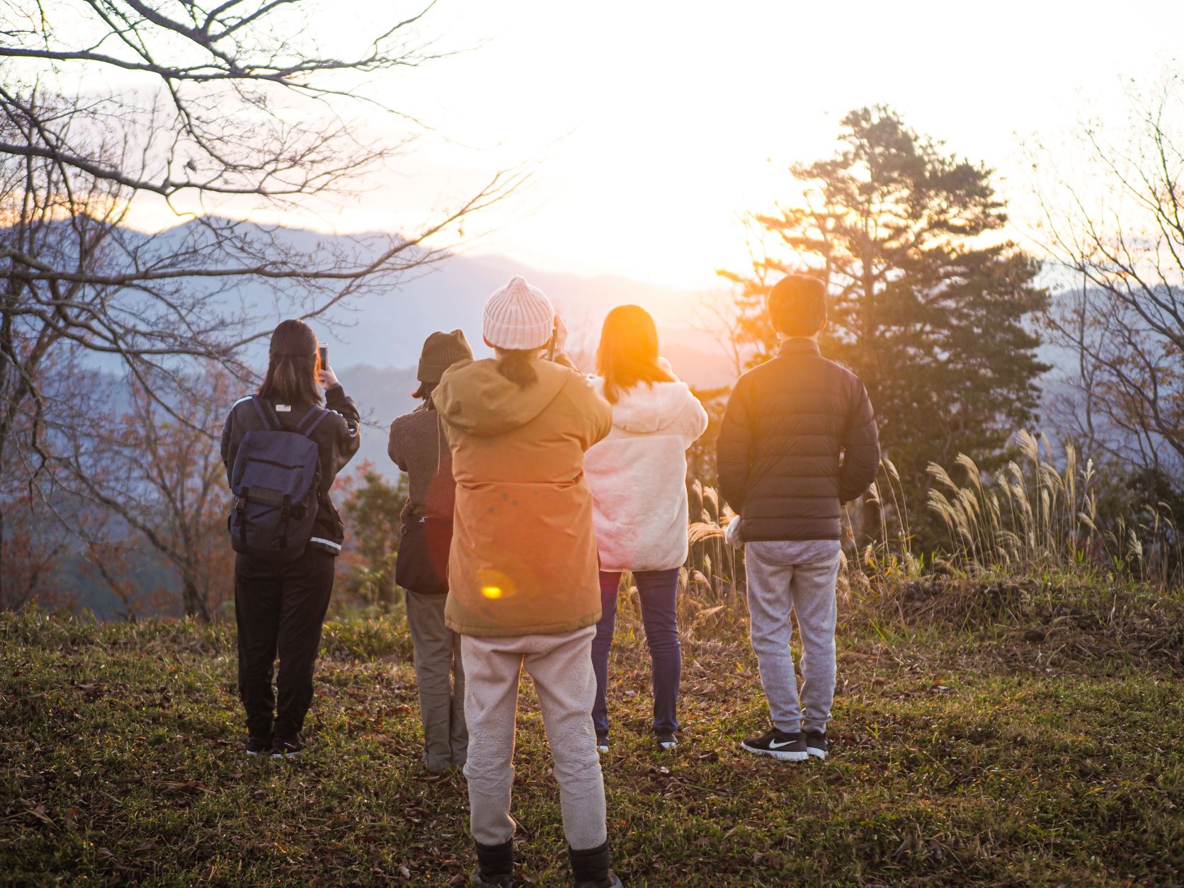ツアー参加者が、山頂から朝日をながめたり写真を撮っている