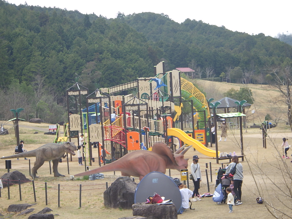 大型恐竜遊具で親子連れが遊んでいる