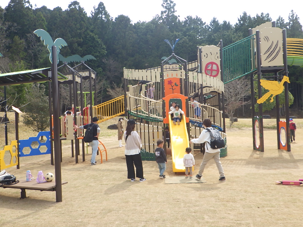 すべり台をこどもたちがすべっていて親が下で待っている