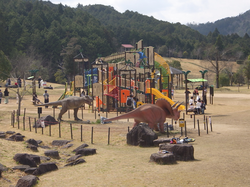 恐竜が2体立っていてその奥に大型の恐竜遊具がある