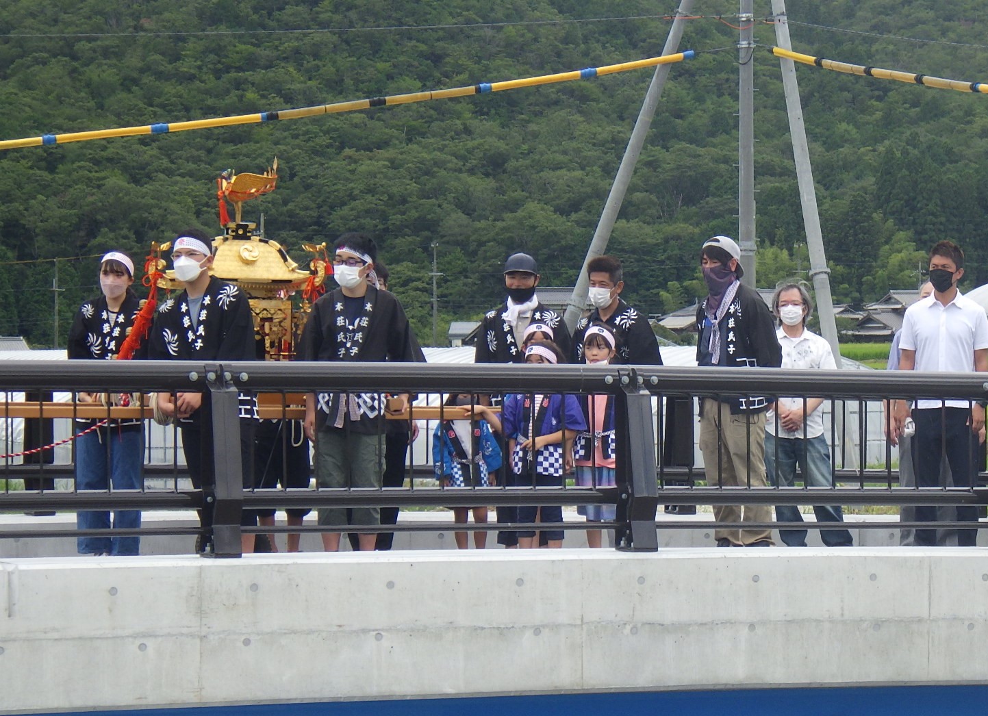 橋の渡り初めで、ハッピを着たこどもたちや大人が神輿を引っ張って歩いている