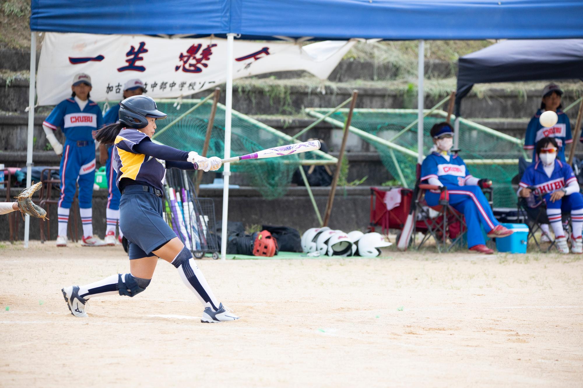 ソフトボールのユニフォームを着た女の子がバットをスイングしている