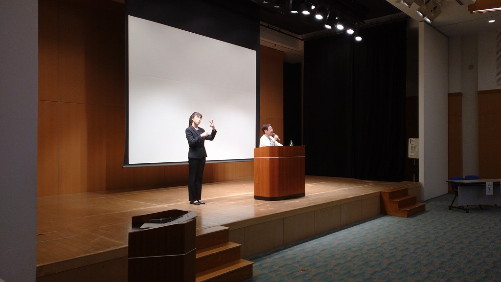 講演会で、舞台中央の演題で女性が話をしていて、その隣に手話通訳者が通訳している