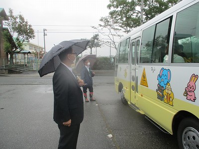 小さい傘で訓練を見守る教育長